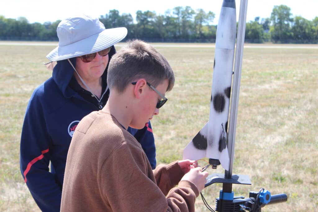 Volunteer and child working on model rocket
